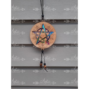 Könnte beinhalten: Ein hölzerner Pentagramm-Anhänger mit einem regenbogenfarbenen, irisierenden Finish und einer schwarzen Schnur mit braunen und schwarzen Perlen. Der Anhänger hängt an einer Holzwand.