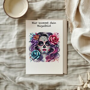 Könnte beinhalten: Eine weiße Karte mit dem Text "Hier kommt dein Bügelbild" und einer bunten Illustration einer Frau mit einem Zucker Schädel Gesicht umgeben von Blumen.