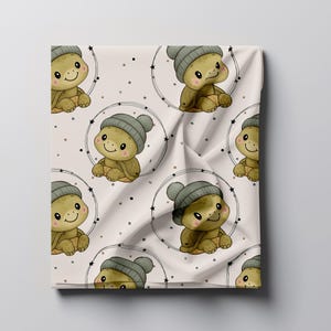 Könnte beinhalten: Gefalteter Stoff mit einem sich wiederholenden Muster von Zeichentrickschildkröten, die graue Mützen tragen. Jede Schildkröte befindet sich in einem kreisförmigen Rahmen mit kleinen Sternakzenten. Der Hintergrund ist hellbeige mit verstreuten Punkten.