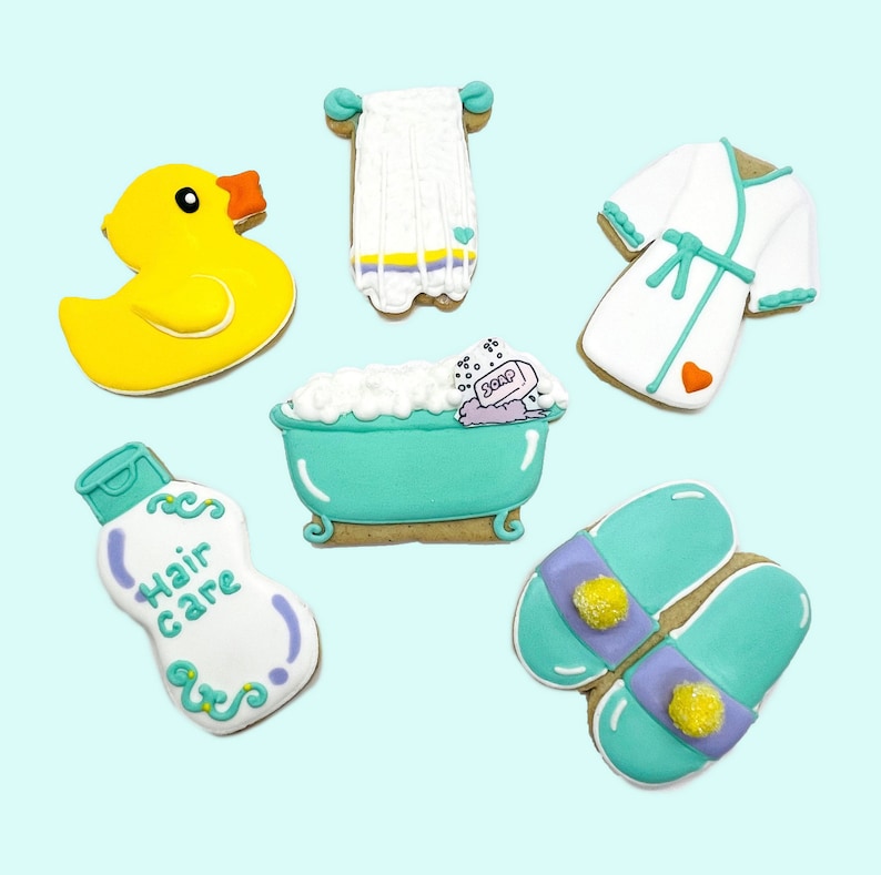 Puede incluir: Un conjunto de siete galletas de az&uacute;car con tem&aacute;tica de ba&ntilde;o. Las galletas est&aacute;n decoradas con varios art&iacute;culos relacionados con el ba&ntilde;o, incluyendo un pato de goma, una bata de ba&ntilde;o, una toalla, una pastilla de jab&oacute;n, una botella de champ&uacute;, una ba&ntilde;era con burbujas y un par de zapatillas.