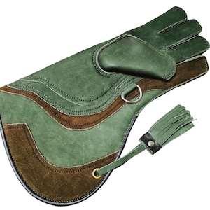 Op de afbeelding: Een groene leren handschoen met een bruin suède paneel en een kwast. De handschoen heeft een uniek ontwerp met een gebogen vorm en een band met een gesp.