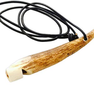 May include: A brown antler whistle with a white mouthpiece, attached to a black leather cord.