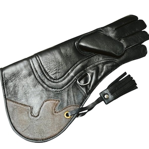 Op de afbeelding: Zwarte leren rijhandschoenen met een kwast en een suède patch op de achterkant van de hand.