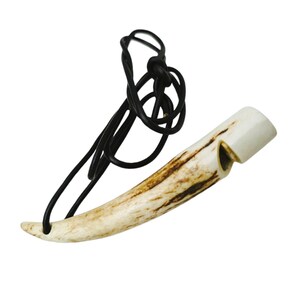 May include: A white antler whistle with a black leather cord. The whistle is shaped like a curved horn and has a small hole on the side for blowing.