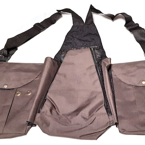 Könnte beinhalten: Eine braune Canvas-Jagdweste mit mehreren Taschen und verstellbaren Trägern. Die Weste hat ein Mesh-Rückenteil für Belüftung.
