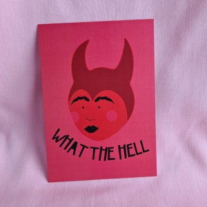 May include: A red card with a cartoon devil face and the text "WHAT THE HELL" in black.
