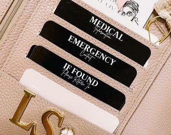 May include: A light pink leather planner with gold hardware and a gold "LS" charm. The planner has a zipper closure and several pockets for cards and other items. The planner is open and there are several cards inside, including a card that says "Bad Vibes Don't Go With My Vibe", a card that says "Medical Information", a card that says "Emergency Contact", and a card that says "If Found Please Return To".
