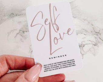 May include: A white card with the words "Self Love" written in pink script. The card also includes a reminder that "Self-love is the foundation and basis for all the love that flows from our hearts to others. To love others we must fall in love with ourselves first."