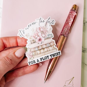 May include: A sticker with a stack of books, flowers, and the text "It's never too late for a plot twist".