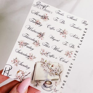 Peut inclure: Une feuille d'autocollants avec un motif floral. Les autocollants présentent diverses phrases liées au café et à la planification, notamment "Coffee Time", "This Week" et "Coffee & Clock". Les autocollants sont conçus pour être utilisés dans un agenda ou un journal.