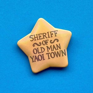 Può includere: Un bottone dorato a forma di stella con la scritta "SHERIFF ~OF~ OLD MAN YAOI TOWN" stampata su di esso.