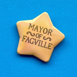 May include: A yellow star-shaped button with the text "Mayor of Fagville" in brown lettering.