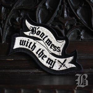 Peut inclure: Écusson brodé noir et blanc avec le texte "Don't mess with the mj" en police gothique. Le patch présente un motif de bannière avec des épées croisées et une bordure décorative. Le patch est probablement destiné aux vêtements ou accessoires.