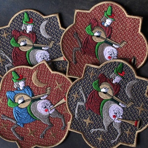 Peut inclure: Écussons brodés représentant un musicien médiéval jouant du luth, chevauchant une créature fantastique avec une trompette. Les écussons sont en forme de quadrilobe avec un fond étoilé rouge et bleu marine.