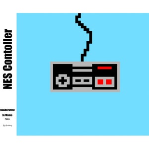 May include: A pixel art illustration of a gray NES controller with a red button and a black cord on a light blue background. The text "NES Controller" is on the left side of the image and the text "Handcrafted in Maine" is below the controller.