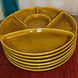 May include: A set of six brown ceramic serving dishes with five individual compartments. The dishes are stacked on top of each other.