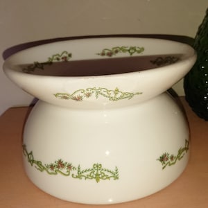 Peut inclure: Un bol en céramique blanche avec un motif floral vert et brun. Le bol a un dessus large et peu profond et une base étroite.