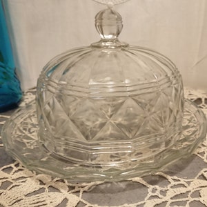 May include: A clear glass butter dish with a domed lid and a matching plate. The dish has a diamond pattern.