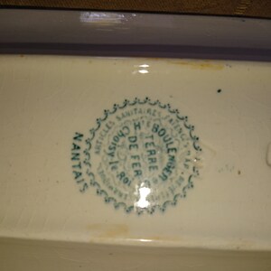 May include: Close-up of a green and white ceramic stamp with the text "Articles Sanitaires Anciens, Choisy le Roi, H. Boule, Terre de Fer, Manufacture de Terre de Fer, Nantais"