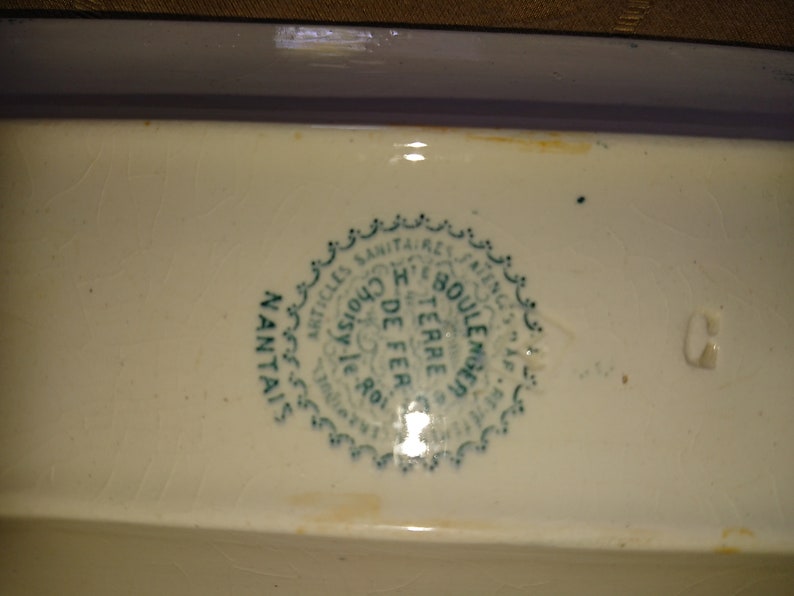 May include: Close-up of a green and white ceramic stamp with the text "Articles Sanitaires Anciens, Choisy le Roi, H. Boule, Terre de Fer, Manufacture de Terre de Fer, Nantais"