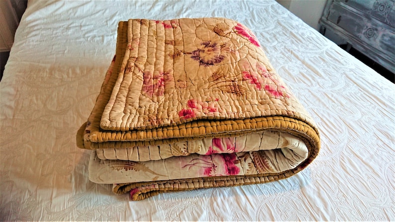 May include: A folded floral patterned quilt with a gold trim. The quilt is made of a soft, lightweight fabric and is perfect for adding a touch of vintage charm to any bedroom.