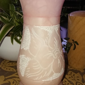 Peut inclure: Un vase en albâtre rose avec un motif floral sculpté. Le vase a une large ouverture et une base arrondie.