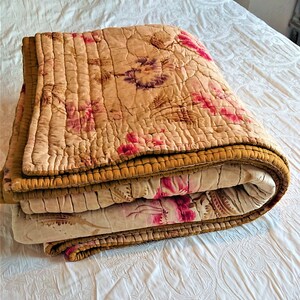 May include: A folded floral patterned quilt with a brown border. The quilt is made of a soft, lightweight fabric and is perfect for adding a touch of vintage charm to any bedroom.