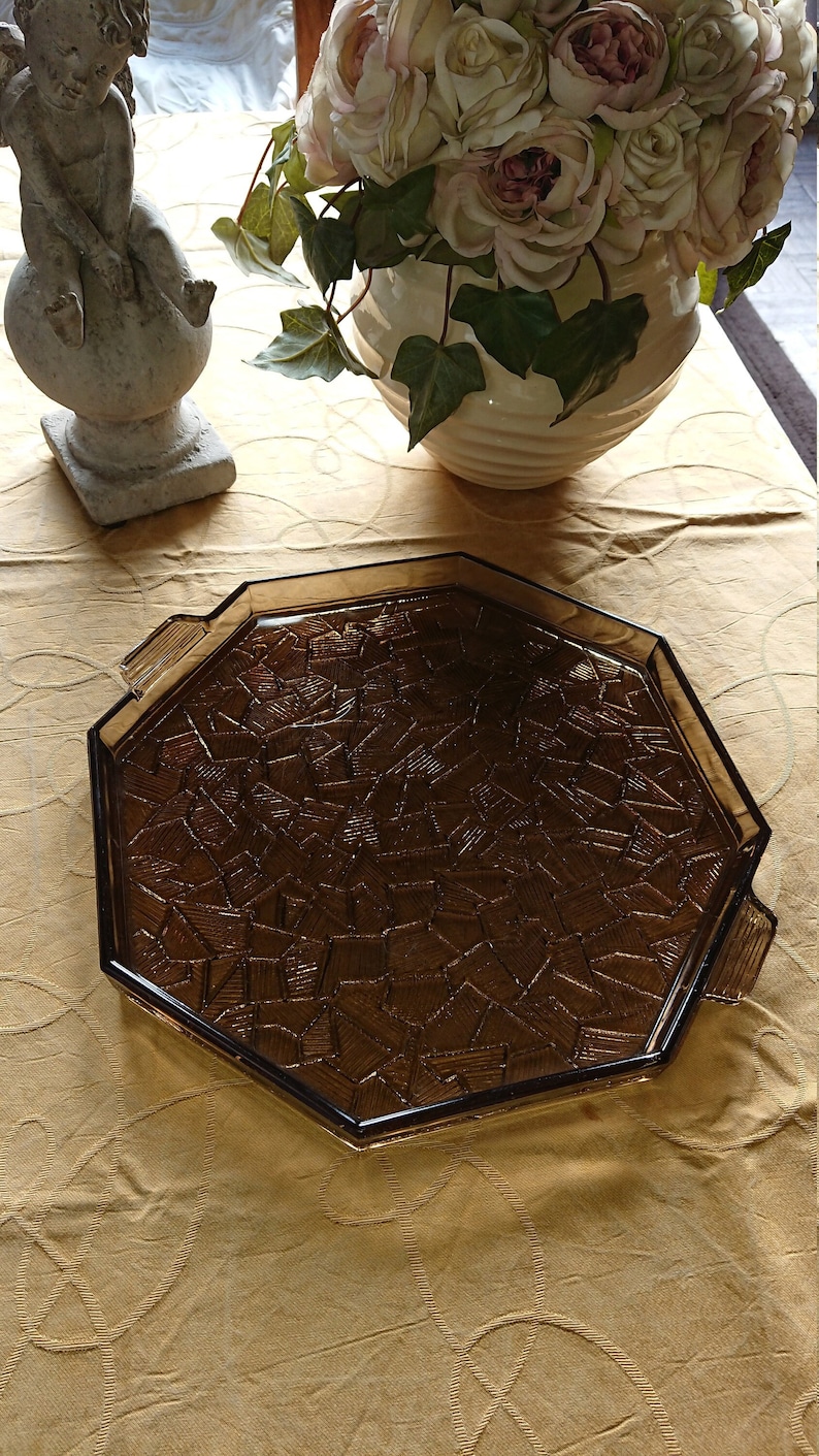 May include: Octagonal brown glass serving tray with a geometric pattern. The tray has a raised edge and two handles.
