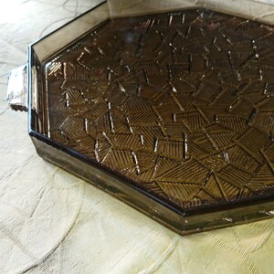 May include: Octagonal glass serving tray with a brown, geometric pattern. The tray has a raised edge and a smooth, polished surface.