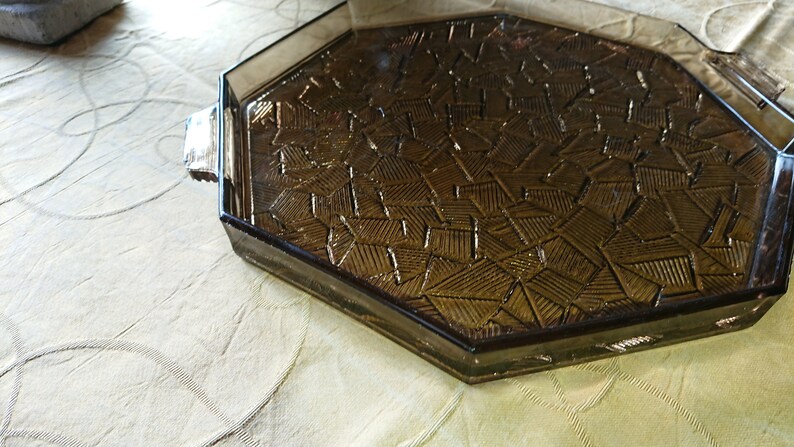 May include: Octagonal glass serving tray with a brown, geometric pattern. The tray has a raised edge and a smooth, polished surface.