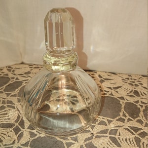 May include: A clear glass bottle with a faceted stopper. The bottle has a round body with a textured design.