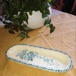 May include: An oval-shaped ceramic dish with a blue and white floral design. The dish has a raised rim and a slightly curved bottom.