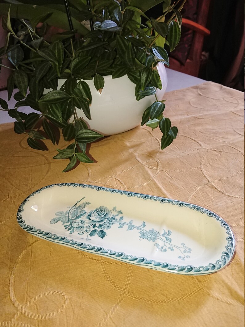 May include: An oval-shaped ceramic dish with a blue and white floral design. The dish has a raised rim and a slightly curved bottom.
