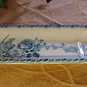 May include: An oval ceramic dish with a blue and white floral design. The dish has a raised rim and a divided interior.