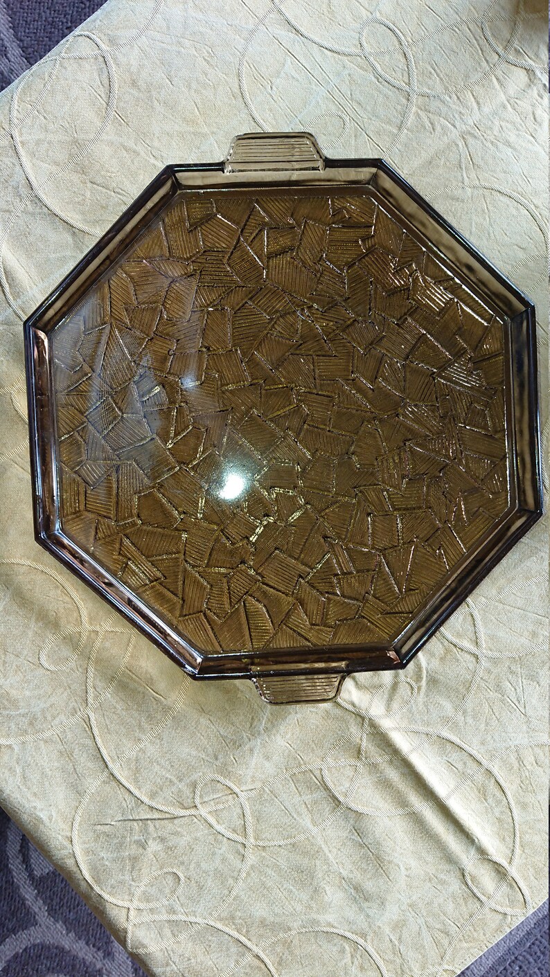 May include: Octagonal brown glass serving tray with a geometric pattern. The tray has a raised edge and two handles.