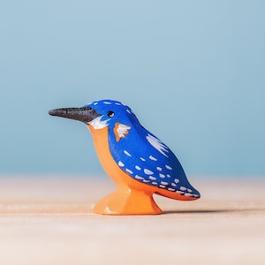 Vibrantly painted wooden kingfisher toy in blue and orange, part of BumbuToys’ Birds Collection, standing against a clear blue backdrop, handcrafted to encourage educational play about wildlife.
