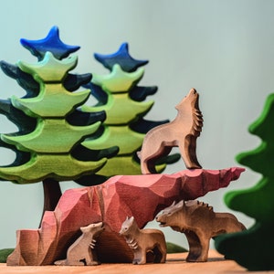 A collection of wooden wolf sculptures in various poses displayed on a honey-toned wooden table, set against a tranquil aqua background.