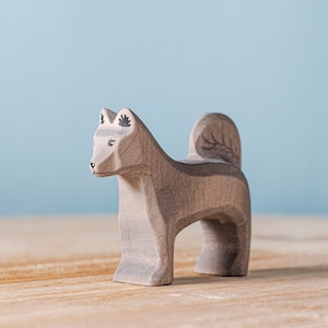 Handcrafted Shurik Dog wooden figurine with intricate leaf patterns, standing on a wooden surface with a pastel blue background, suitable for Montessori education and Waldorf style play