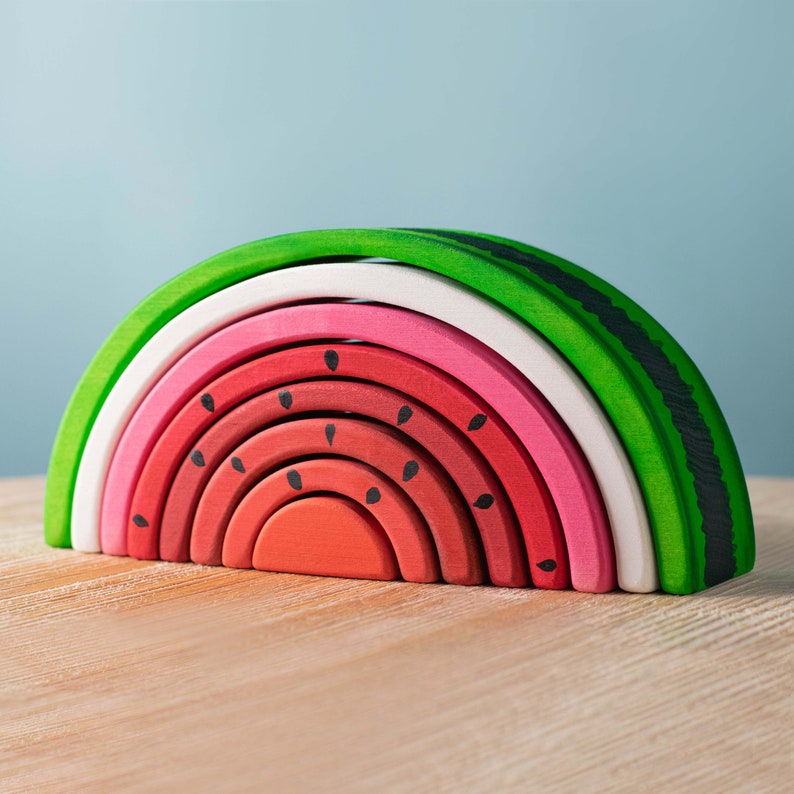 Wooden watermelon stacker toy, colored in shades of green and pink with seed details, Montessori learning.