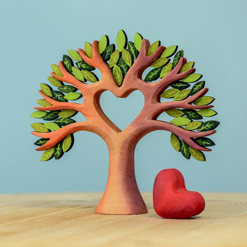 Waldorf handcrafted wooden heart tree with detachable red heart next to the trunk on a light wood surface