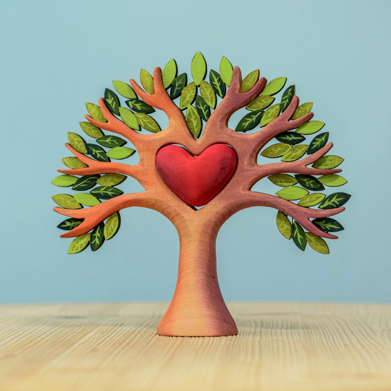 Artisanal wooden heart tree from Waldorf inspired toys featuring detailed leaves and a central heart against a soft blue backdrop