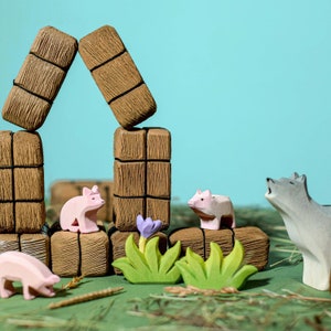 Wooden pig, hedgehog, and wolf figurines among stacked brown logs, green plants, and purple flowers.