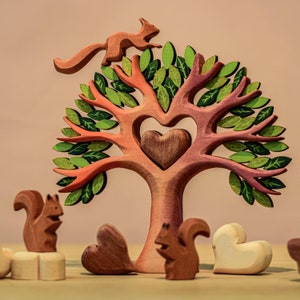 Handcrafted wooden heart tree toy surrounded by various wooden animal figures on a pale surface, illustrating a playful scene