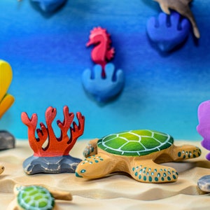 Dynamic underwater scene featuring a pink wooden seahorse figurine with an array of sea creatures and coral formations in a variety of colors.