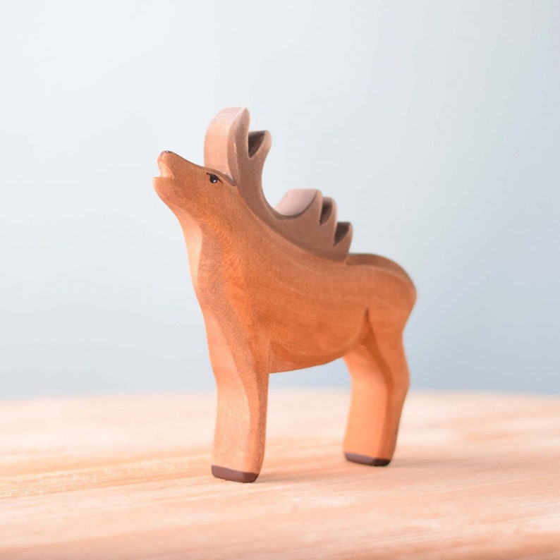 A handmade gift of a stylized deer with a prominent mane stands on a smooth surface against a soft, neutral background.