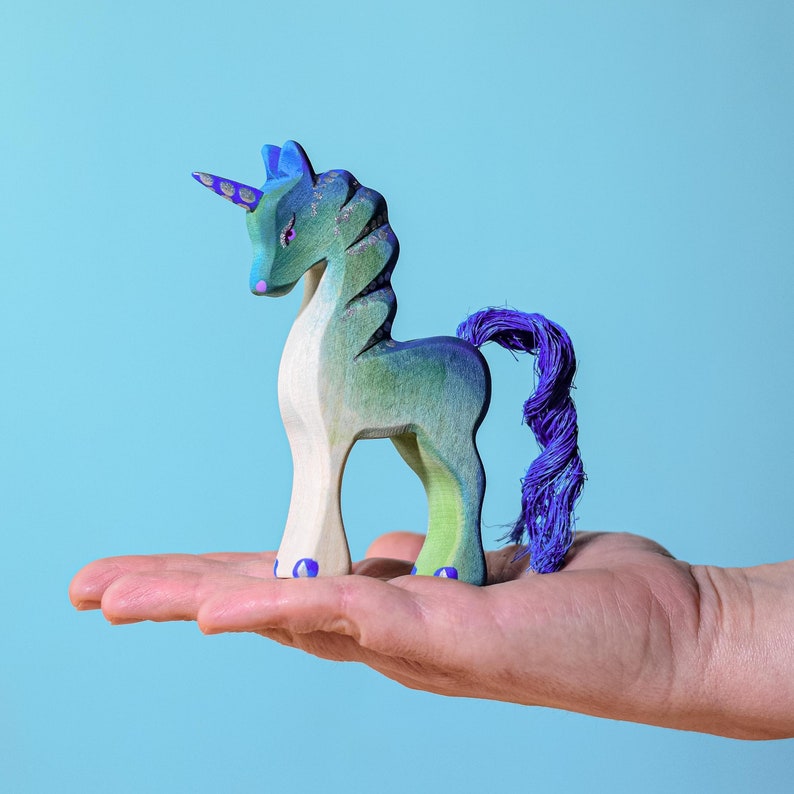 Handcrafted wooden unicorn figurine with a purple tail
