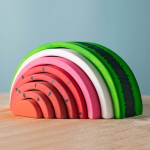 Handcrafted oak watermelon stacking toy with bright green rind and pink interior, educational play.
