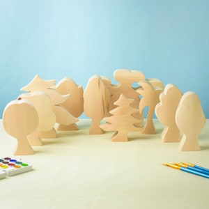 May include: A set of wooden tree shapes in various styles, including a palm tree, a pine tree, and a maple tree. The trees are all unpainted and ready to be decorated.