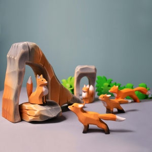 Handcrafted wooden scene with foxes, archways, and foliage, depicting a playful forest environment on a gray surface.