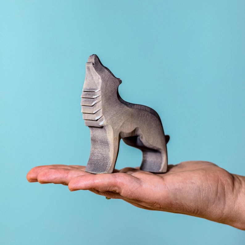 Close-up of a solitary wooden wolf figure mid-howl, with textured carving lines suggesting fur, presented against a calming blue gradient background.